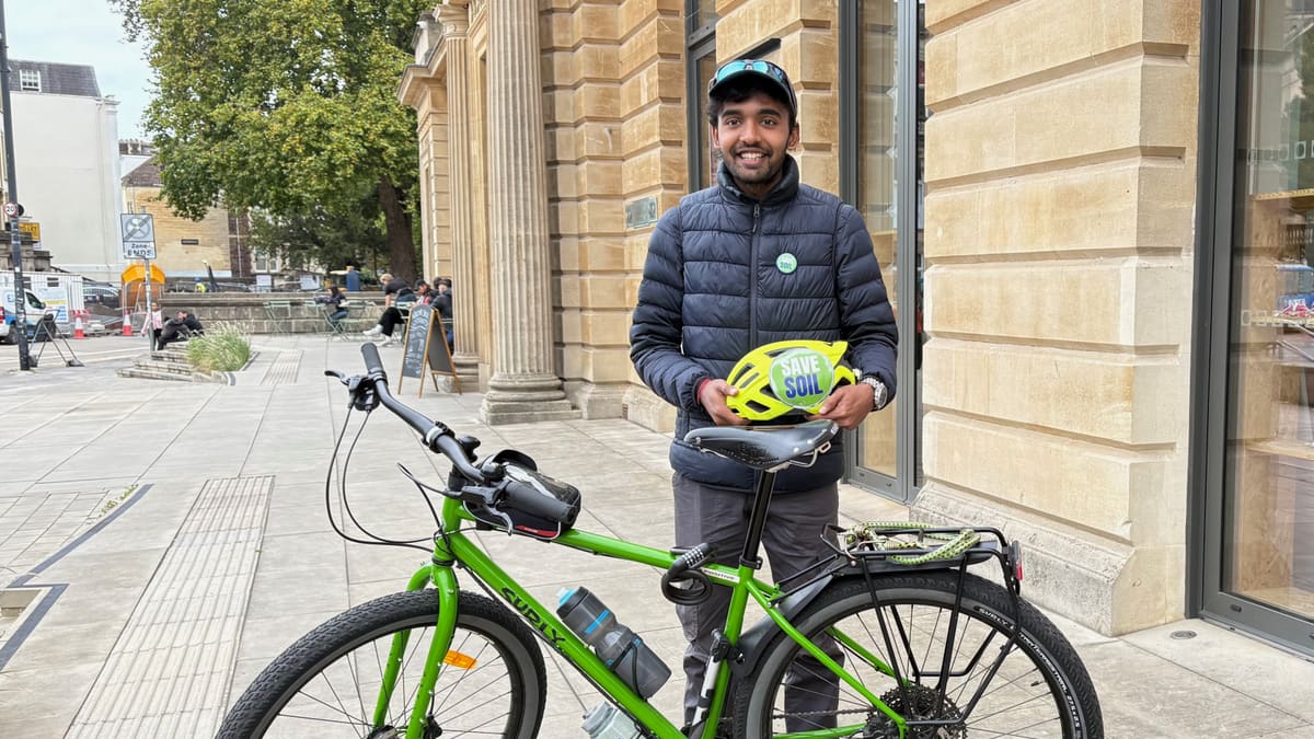 Sahil Jha standing with his loaded touring bicycle outside a stone building